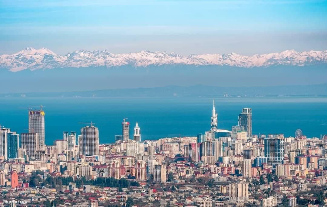 Coastal city skyline with the snow-capped Caucasus range rising in the distance
