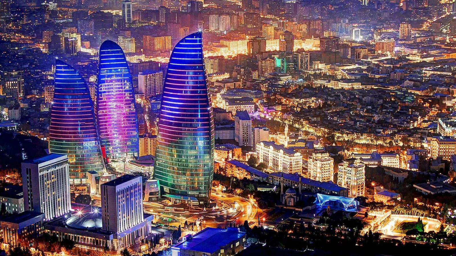 Baku Flame Towers lit up over the Caspian shoreline at night