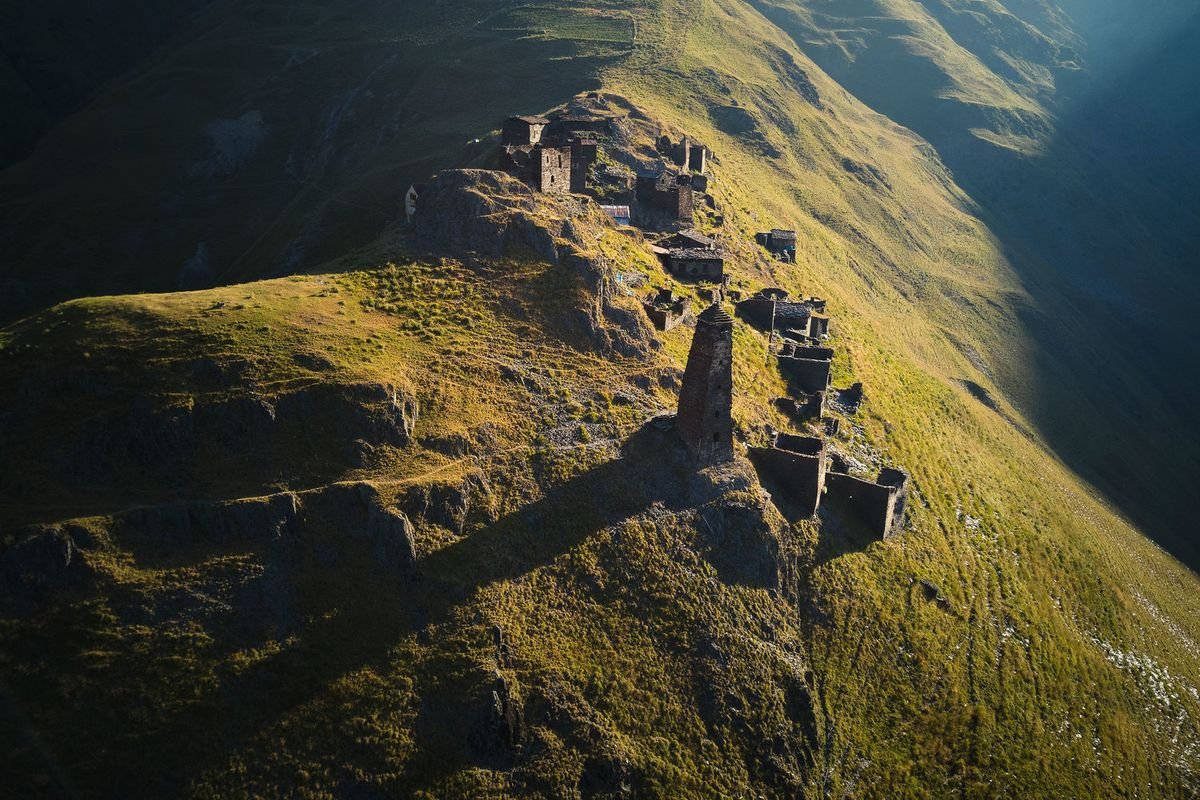 Medieval Tusheti tower-fortresses scattered along a ridge at golden hour